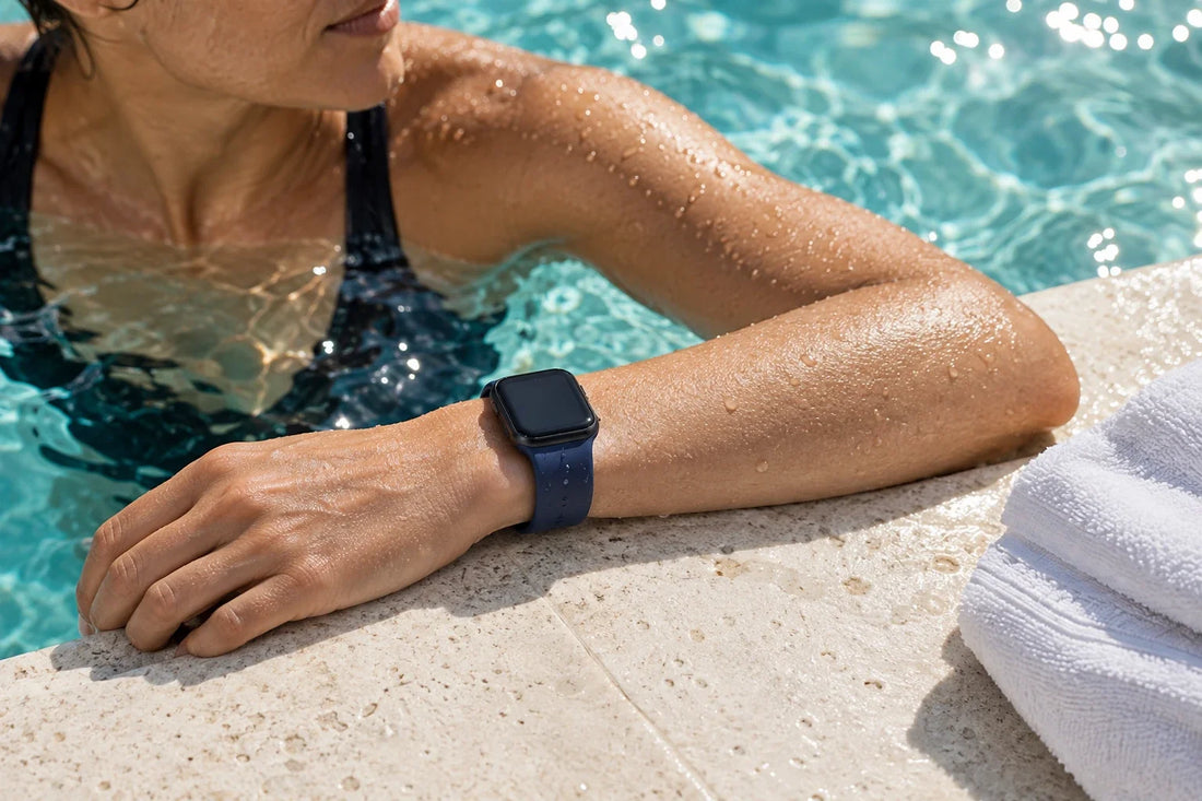 Swimmer resting at a pool edge wearing a navy silicone band on an unbranded smartwatch.