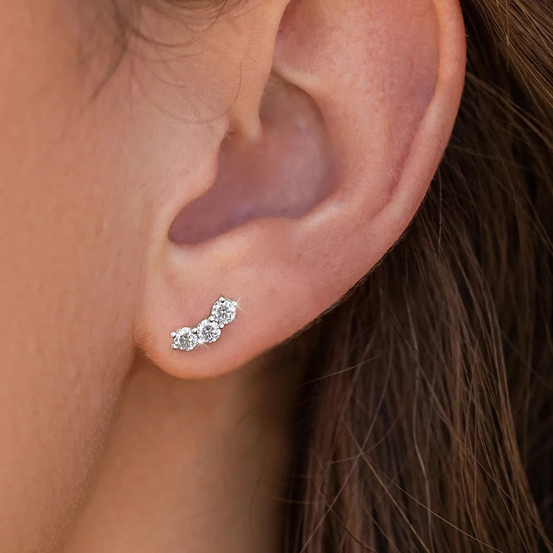 Three-Stone Moissanite Curved Stud Earrings in Sterling Silver — Shown on ear