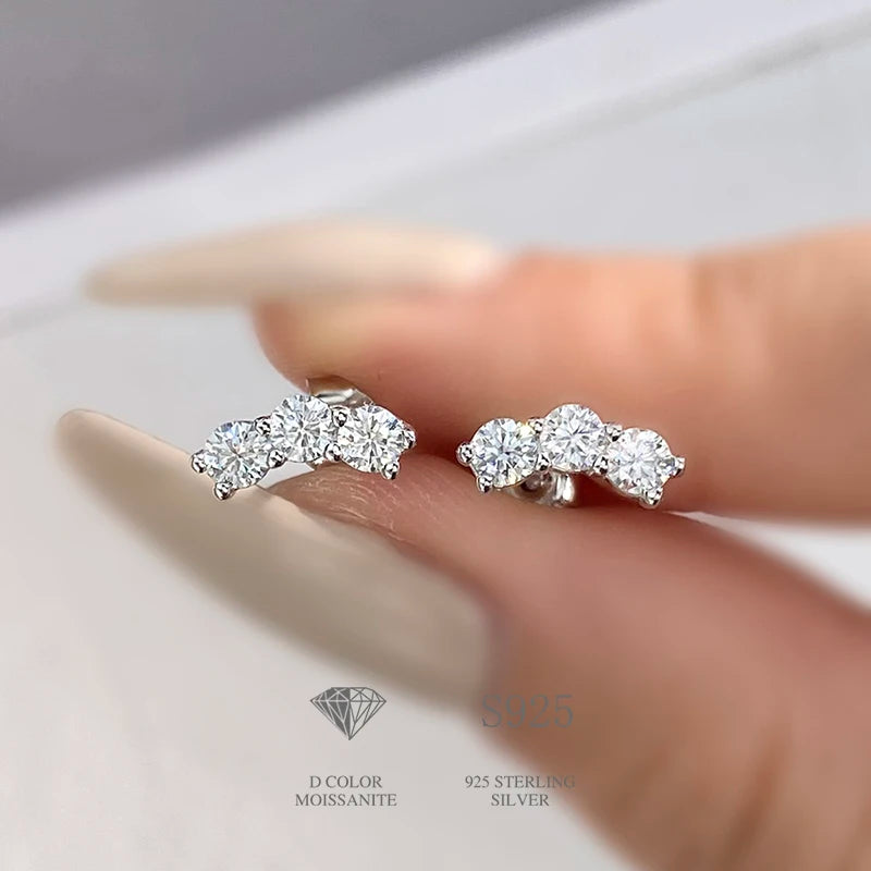Three-Stone Moissanite Curved Stud Earrings in Sterling Silver — Silver curved studs on hand