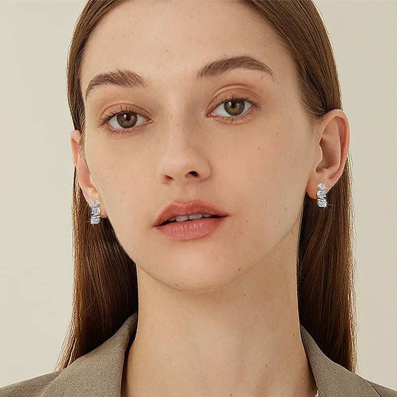 Three-Stone Twist Moissanite Stud Earrings in Sterling Silver - Graduated studs on model