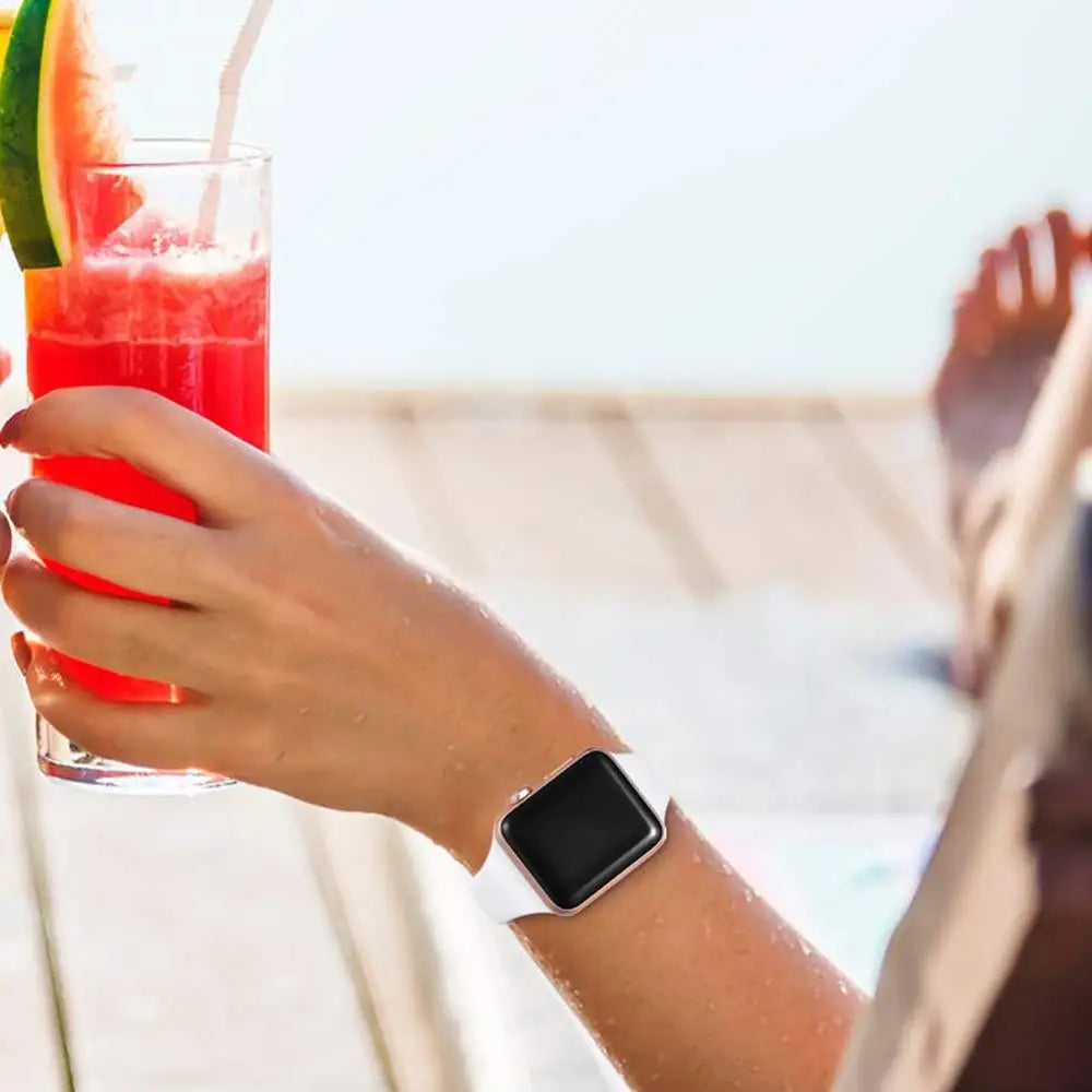 Light-colored slim silicone Apple Watch band worn while holding a drink