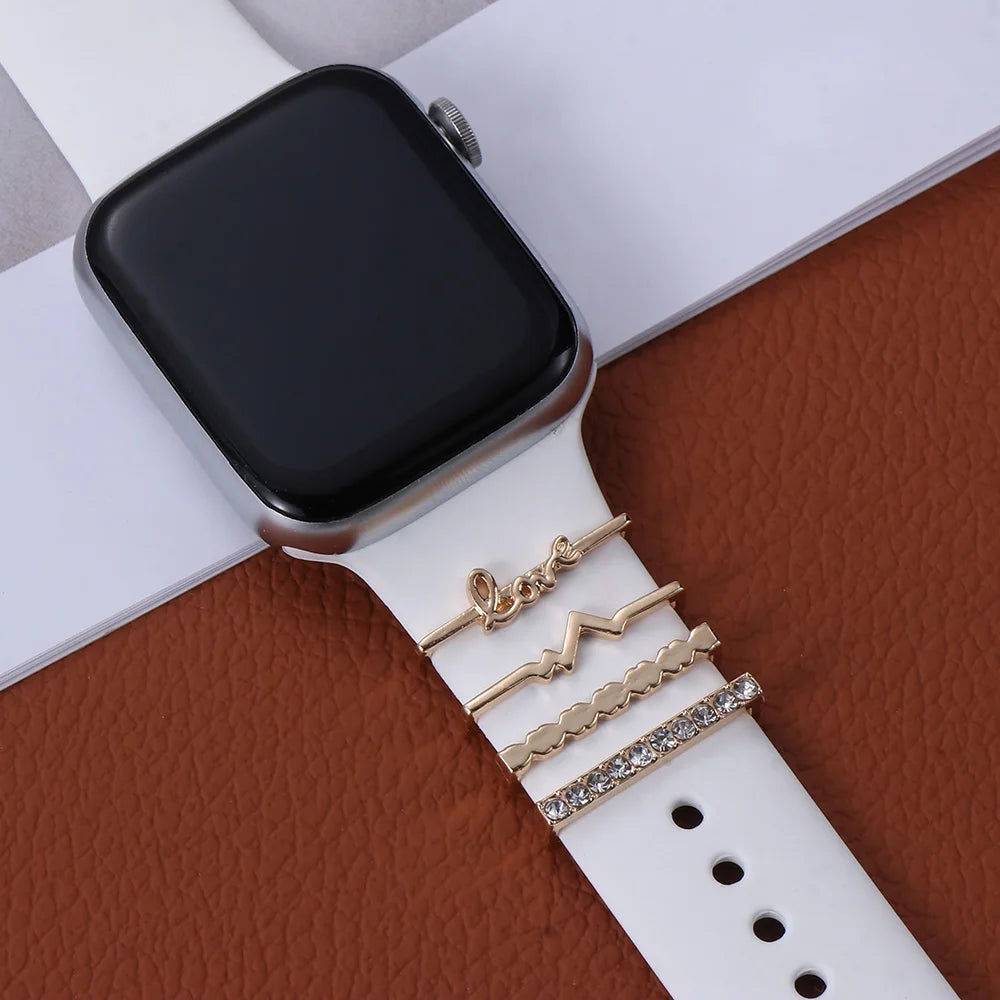 Decorative metal charms on an Apple Watch band adding style and elegance with a white strap.