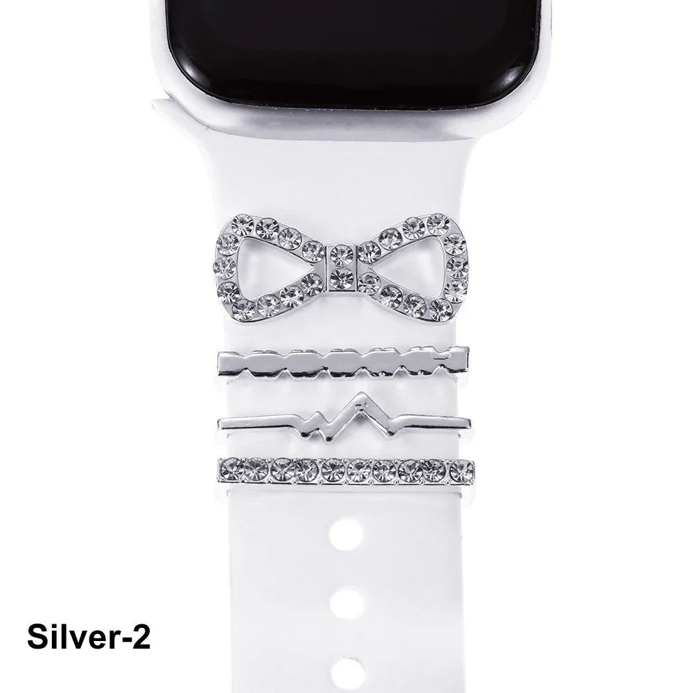 Decorative silver metal charms on a white Apple Watch band, featuring a bow and stylish accents.