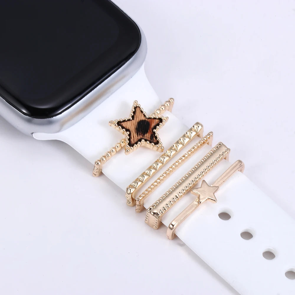 Decorative metal charms on a white Apple Watch band, featuring gold accents and a star design for enhanced style.