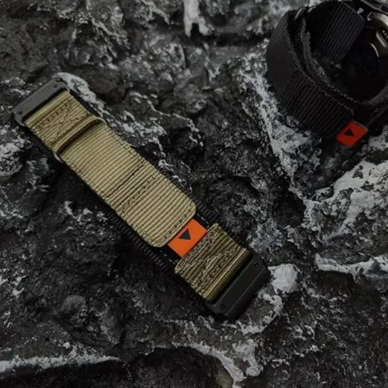 Garmin QuickFit Nylon Loop Band with Orange Tab olive-toned nylon band shown on a textured background