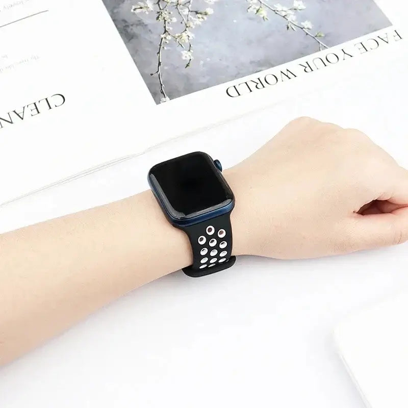 Black and white perforated Apple Watch band worn on wrist