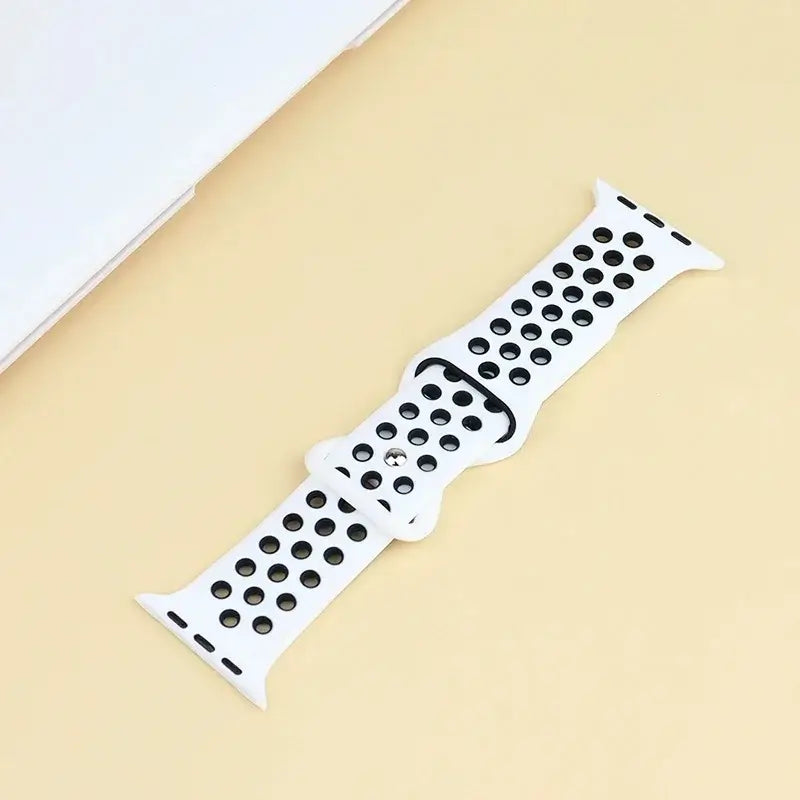 White and black perforated silicone Apple Watch strap laid flat