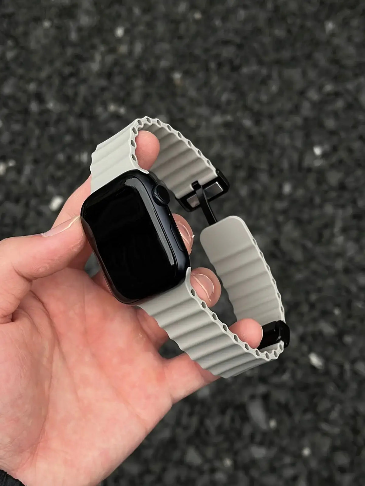 Gray ridged silicone Apple Watch band held open in hand