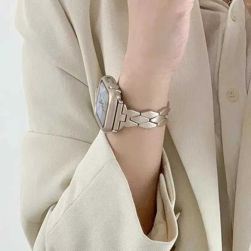 Starlight herringbone Apple Watch band worn on a wrist.