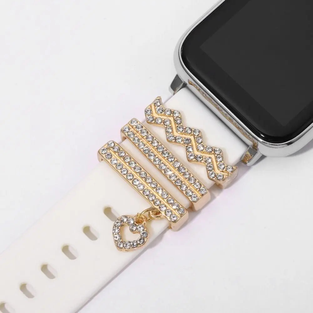 Decorative metal charms on an Apple Watch band, featuring sparkling designs and a heart charm, enhancing style and elegance.