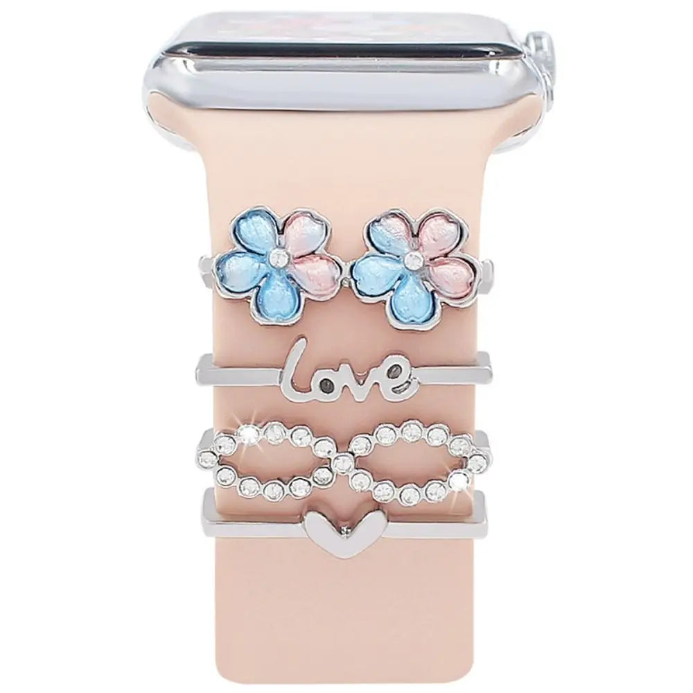 Decorative metal charms for Apple Watch bands featuring floral designs and love motifs in silver and pastel colors.