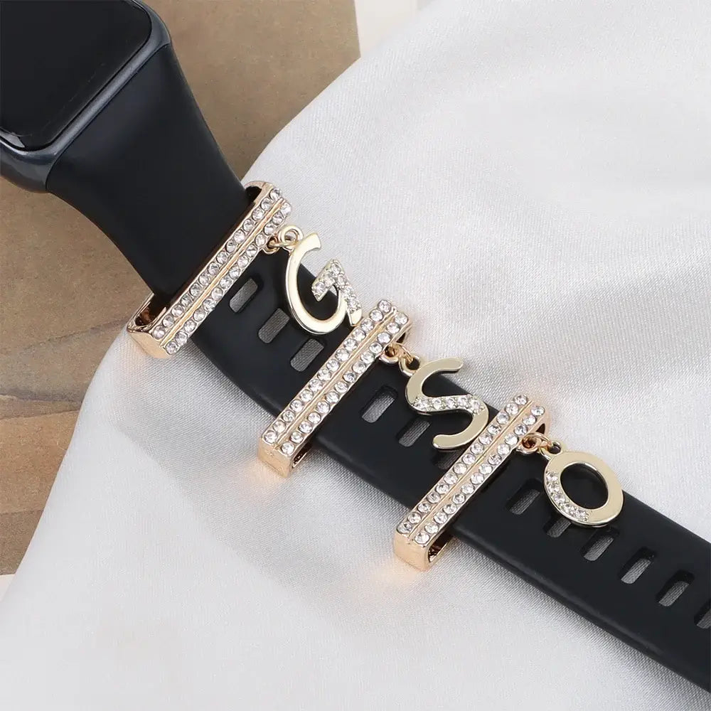 Decorative letter charms with crystals on a black Apple Watch band, adding luxury and style to your smartwatch.