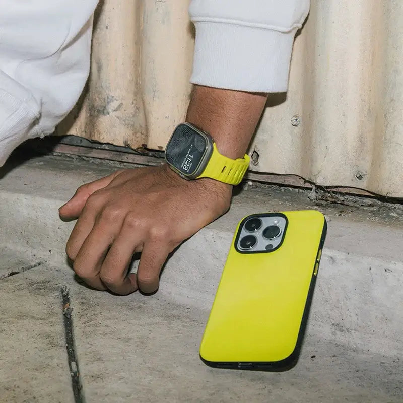 Neon yellow silicone Apple Watch band worn on wrist outdoors