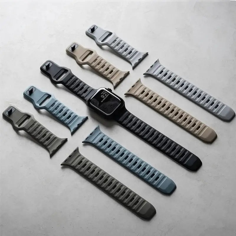 Slotted silicone Apple Watch bands laid flat in neutral colors