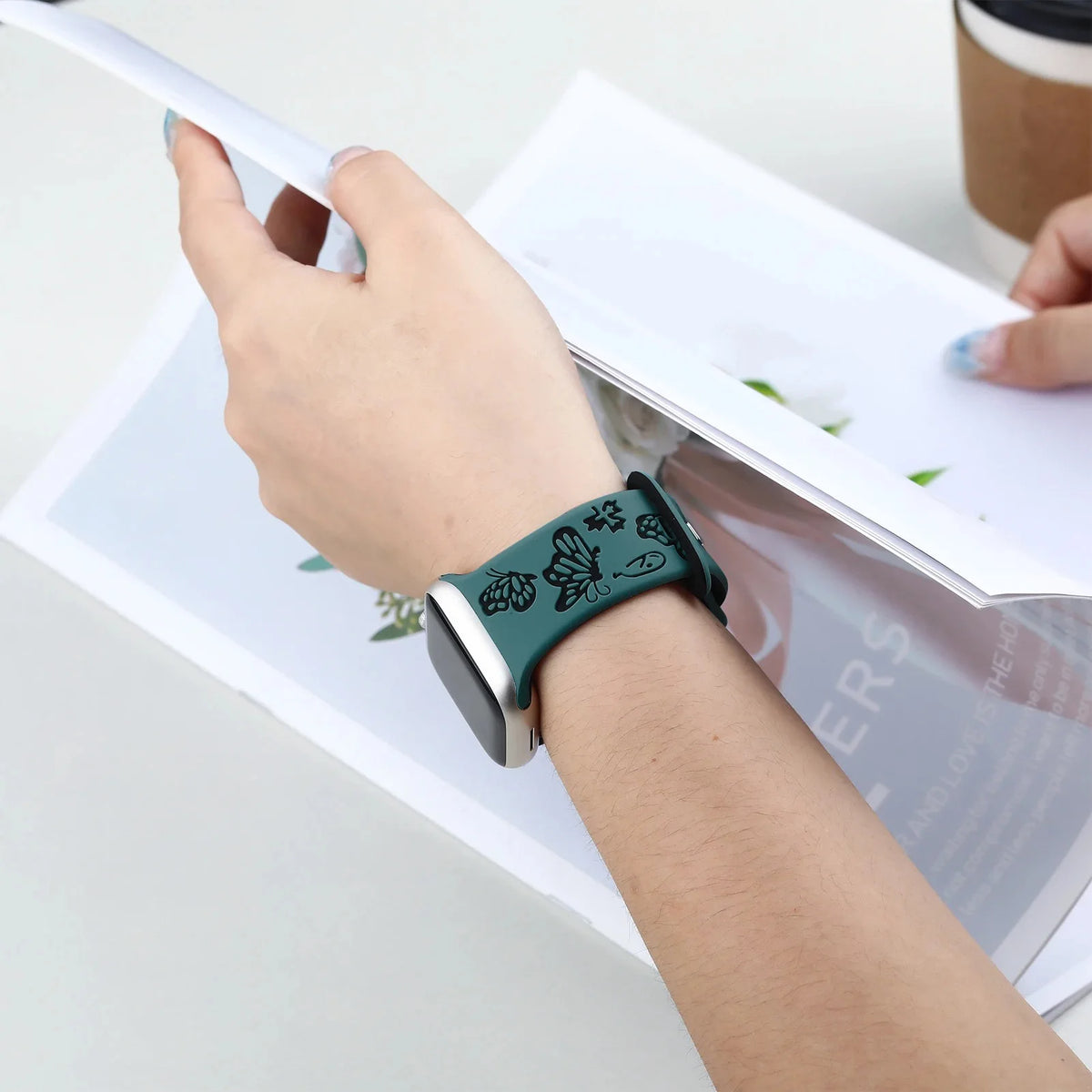 Green butterfly silicone band worn while reading for Apple Watch