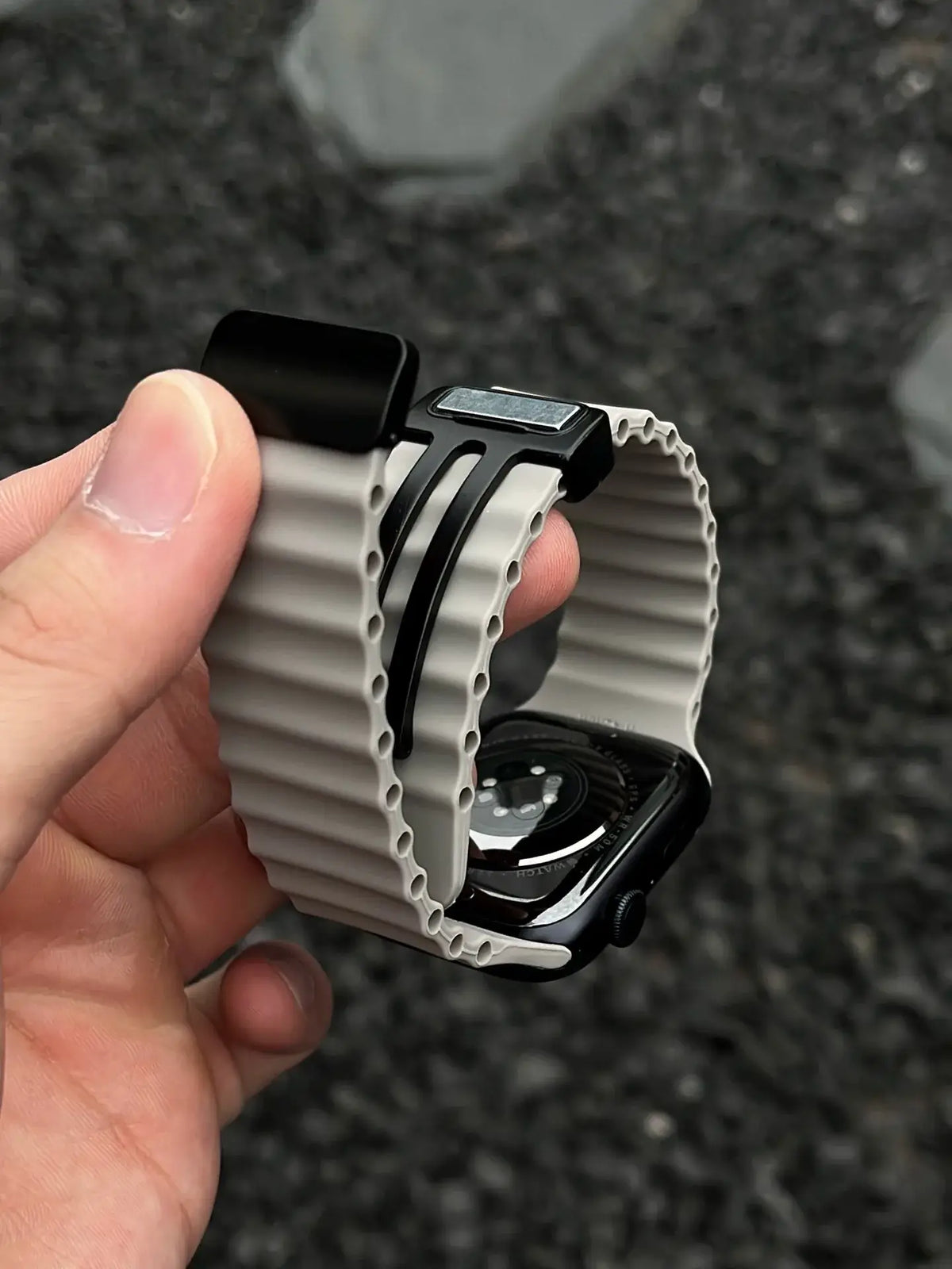 Close-up of gray ridged silicone strap and magnetic clasp held in hand