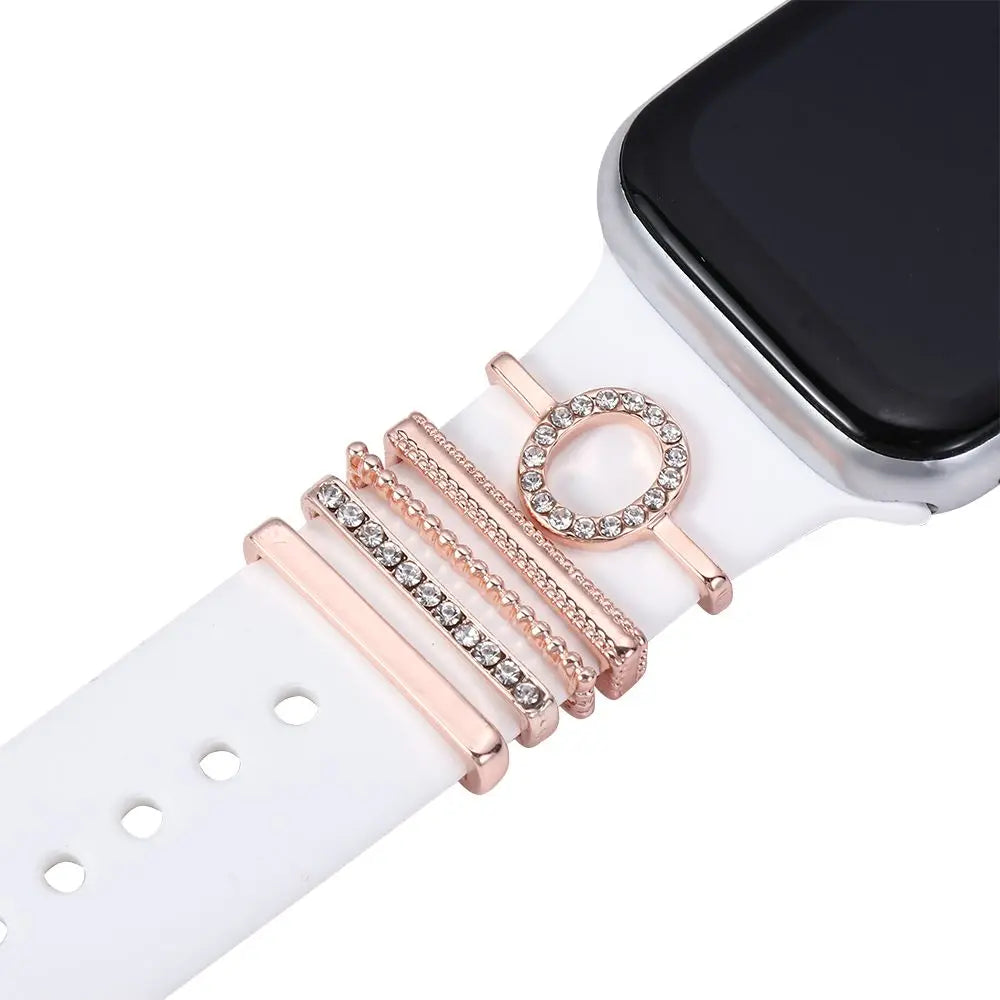 Rose gold decorative metal charms on a white Apple Watch band, adding elegance and style to the smartwatch.