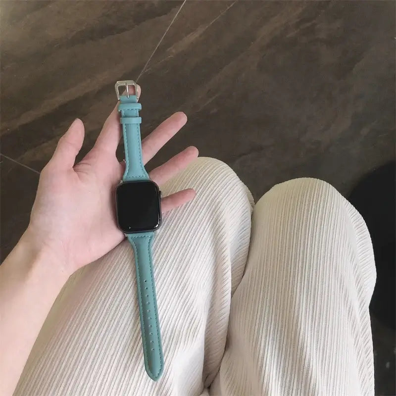 Aqua tapered leather Apple Watch band held in hand