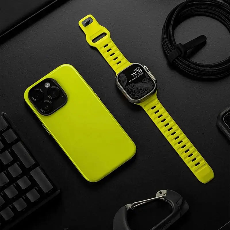 Neon yellow silicone Apple Watch band laid flat beside a phone