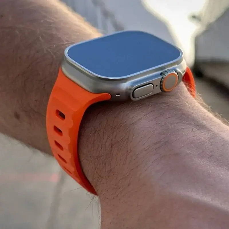 Orange silicone Apple Watch band worn on wrist