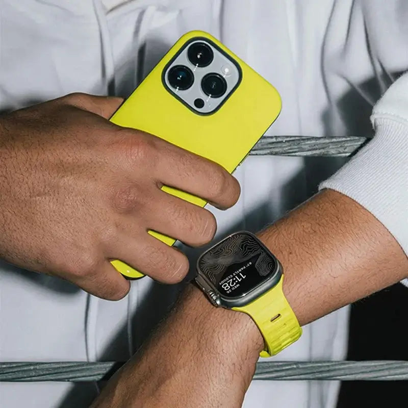 Neon yellow silicone Apple Watch band worn beside a matching phone
