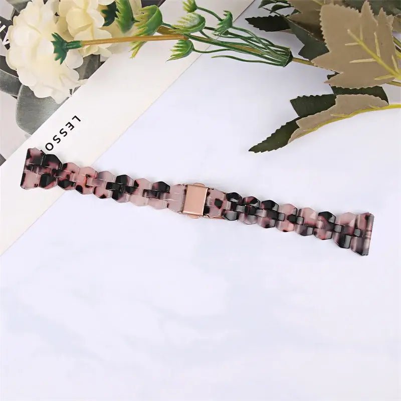 Black and pink marbled resin strap laid flat