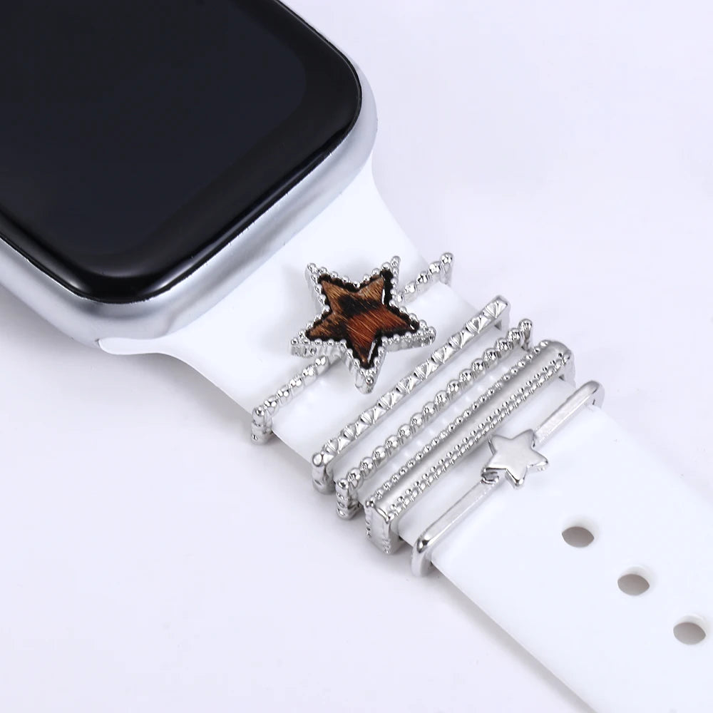 Decorative metal charms featuring star designs on a white Apple Watch band, enhancing style and elegance.