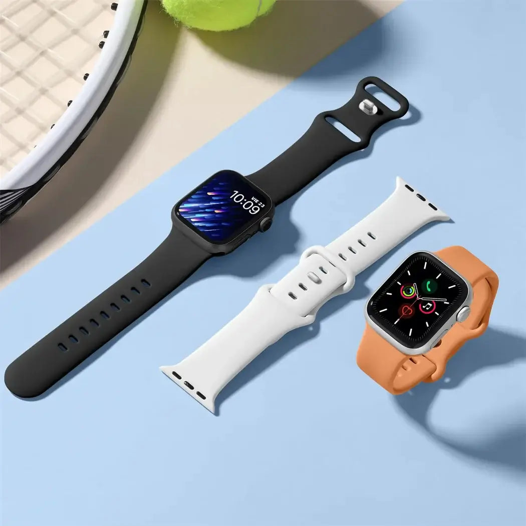 Black, white and orange silicone Apple Watch bands laid flat
