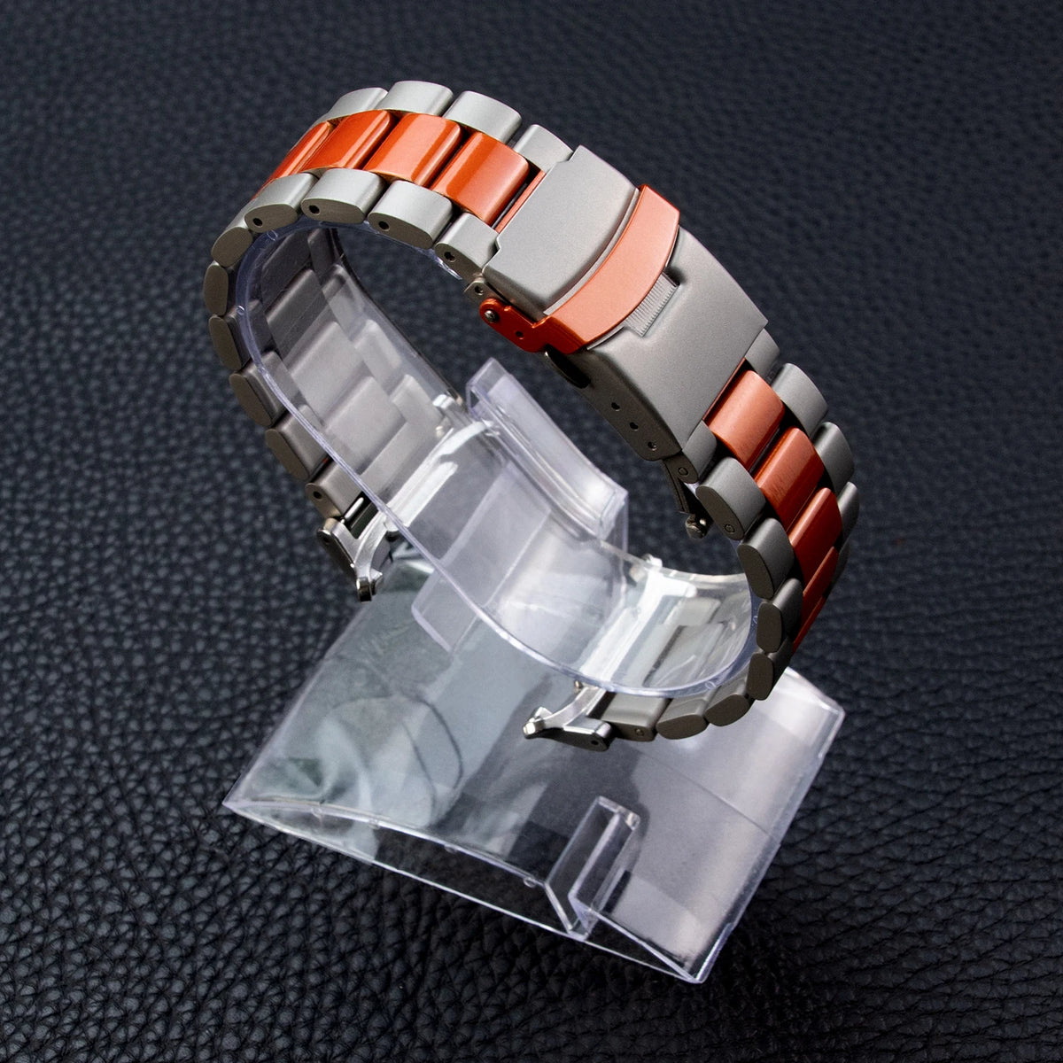 Samsung Galaxy Stainless Steel Link Watch Band - Ultra/Ultra2 displayed on a stand with a sleek orange accent.