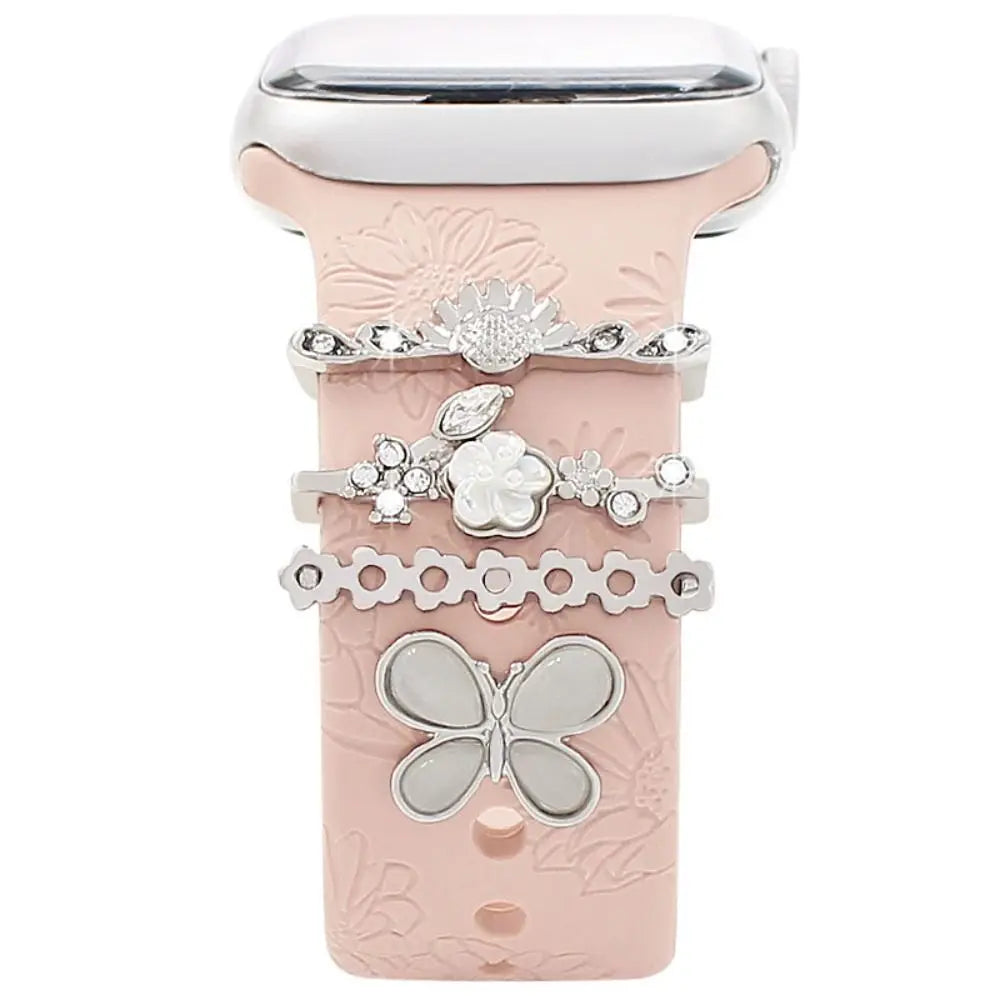 Decorative metal charms on pink Apple Watch band, adding elegance and personality to smartwatch style.