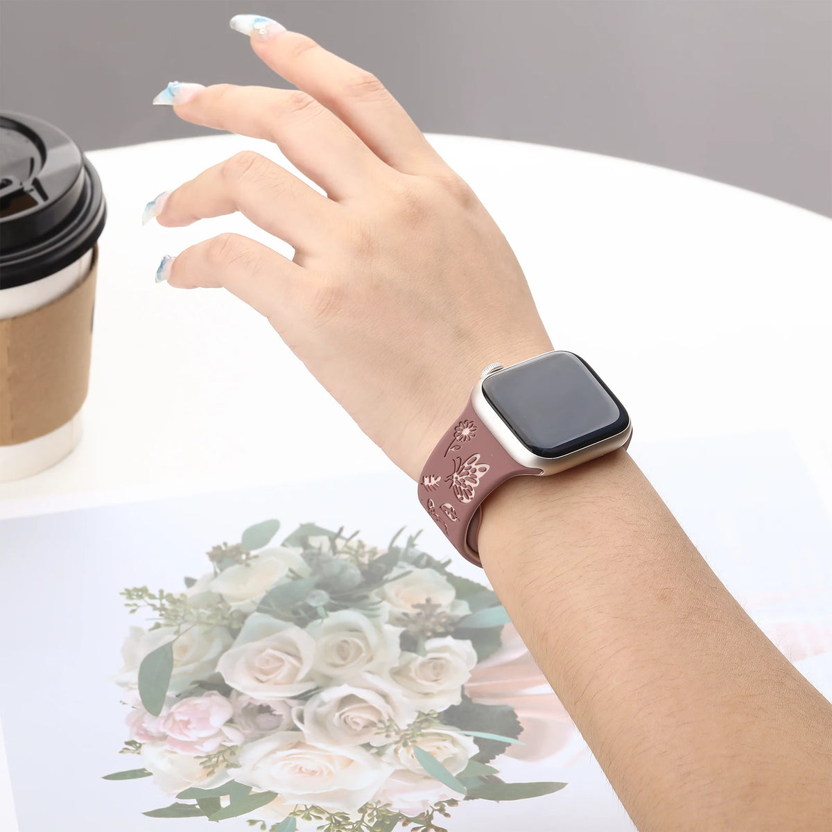 Butterfly silicone band worn on a wrist beside a cup for Apple Watch
