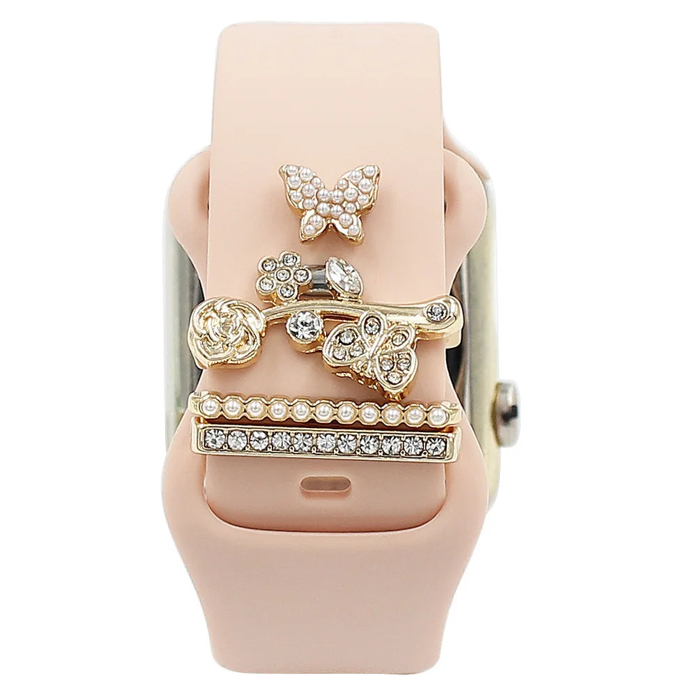 Decorative metal charms on a pink Apple Watch band, adding elegance and flair to smartwatch aesthetics.