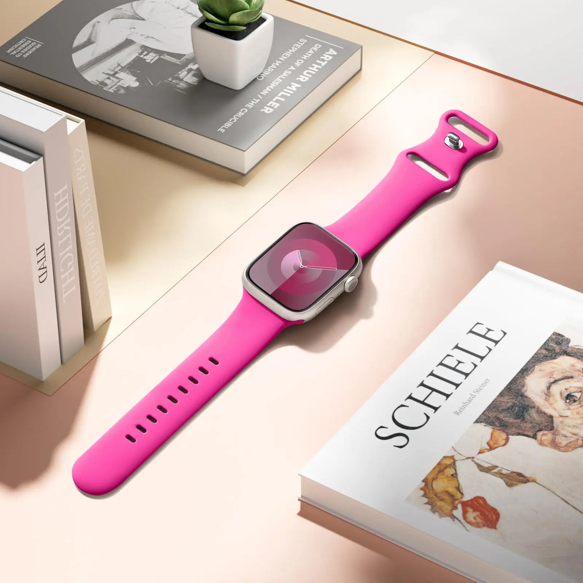 Hot pink silicone band displayed on a desk for Apple Watch