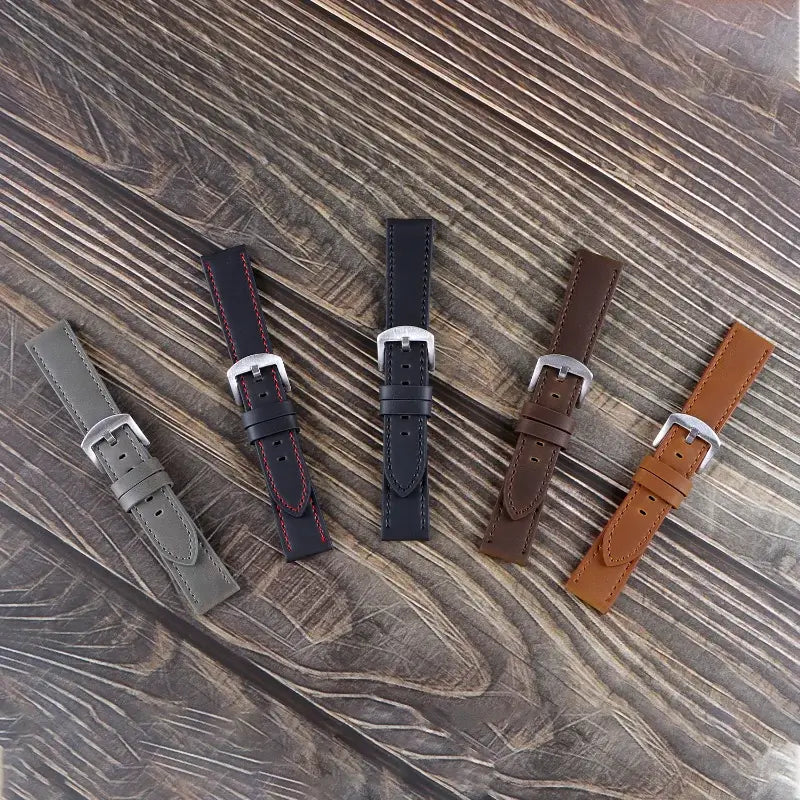 Five leather bands arranged on a wooden surface