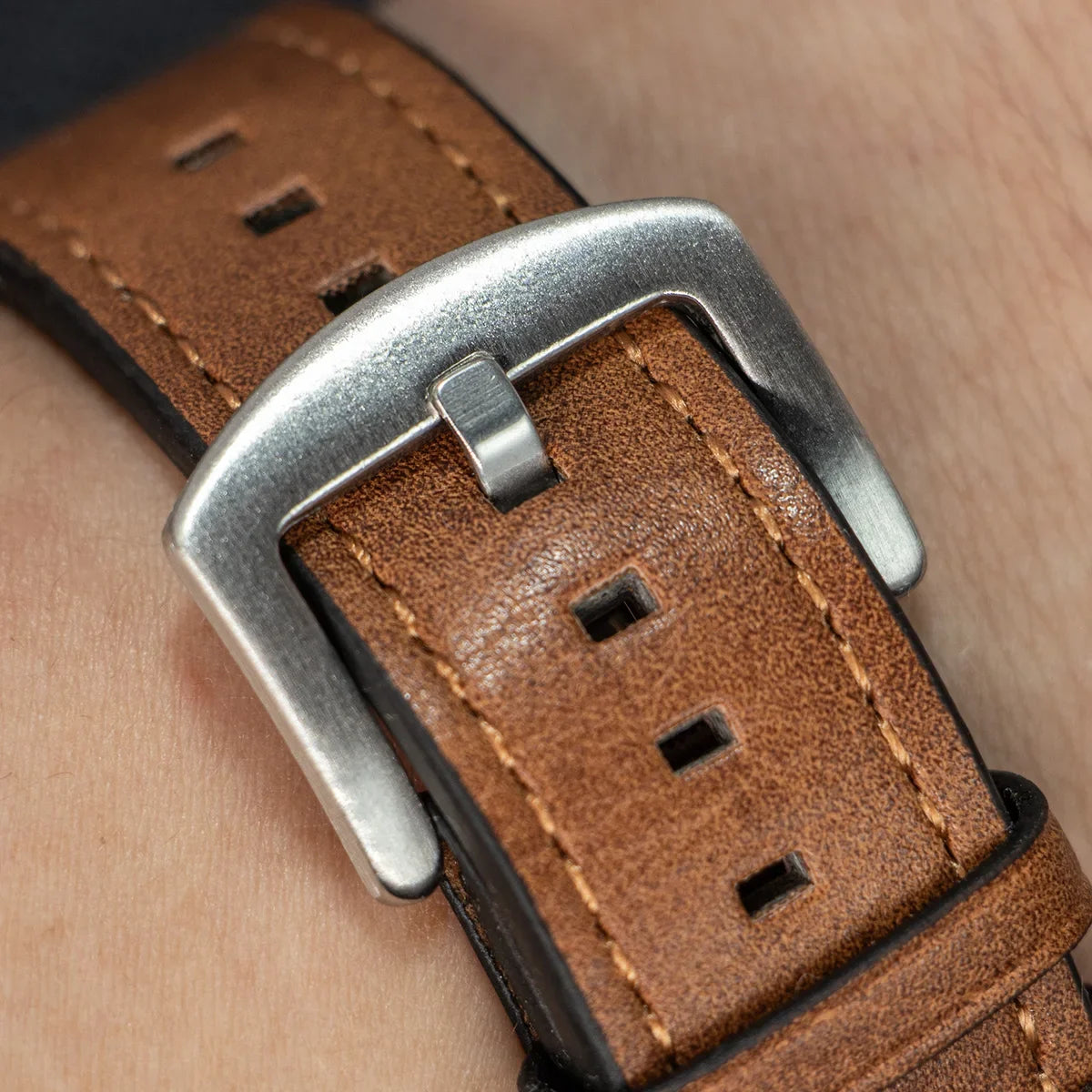 Close-up of metal buckle and stitching on brown leather