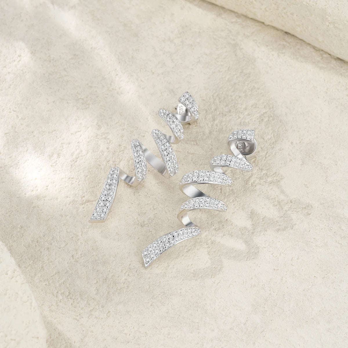 Twisted Spiral Moissanite Drop Earrings in Sterling Silver — Pair on fabric